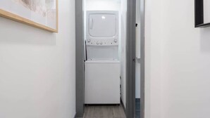 Een smalle gang met een wasmachine en droger in het midden.