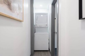 A narrow hallway with a washing machine and dryer in the center. - Super Central Retreat | Steps to Everything! (San Diego)