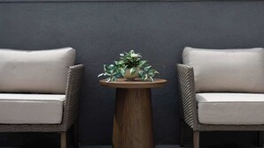 A modern outdoor seating area with two wicker chairs and a wooden table.