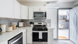 A modern kitchen with white cabinets, a stainless steel stove, a microwave, and a dishwasher.