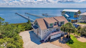 A coastal house with a large deck, a pier extending into the water, and a view of the ocean. - Blessing on the Bay- North Cape Bay Front (Port St. Joe)