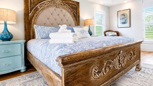 A bedroom with a large bed, a nightstand, a dresser, and a window with blinds. - Blessing on the Bay- North Cape Bay Front (Port St. Joe)