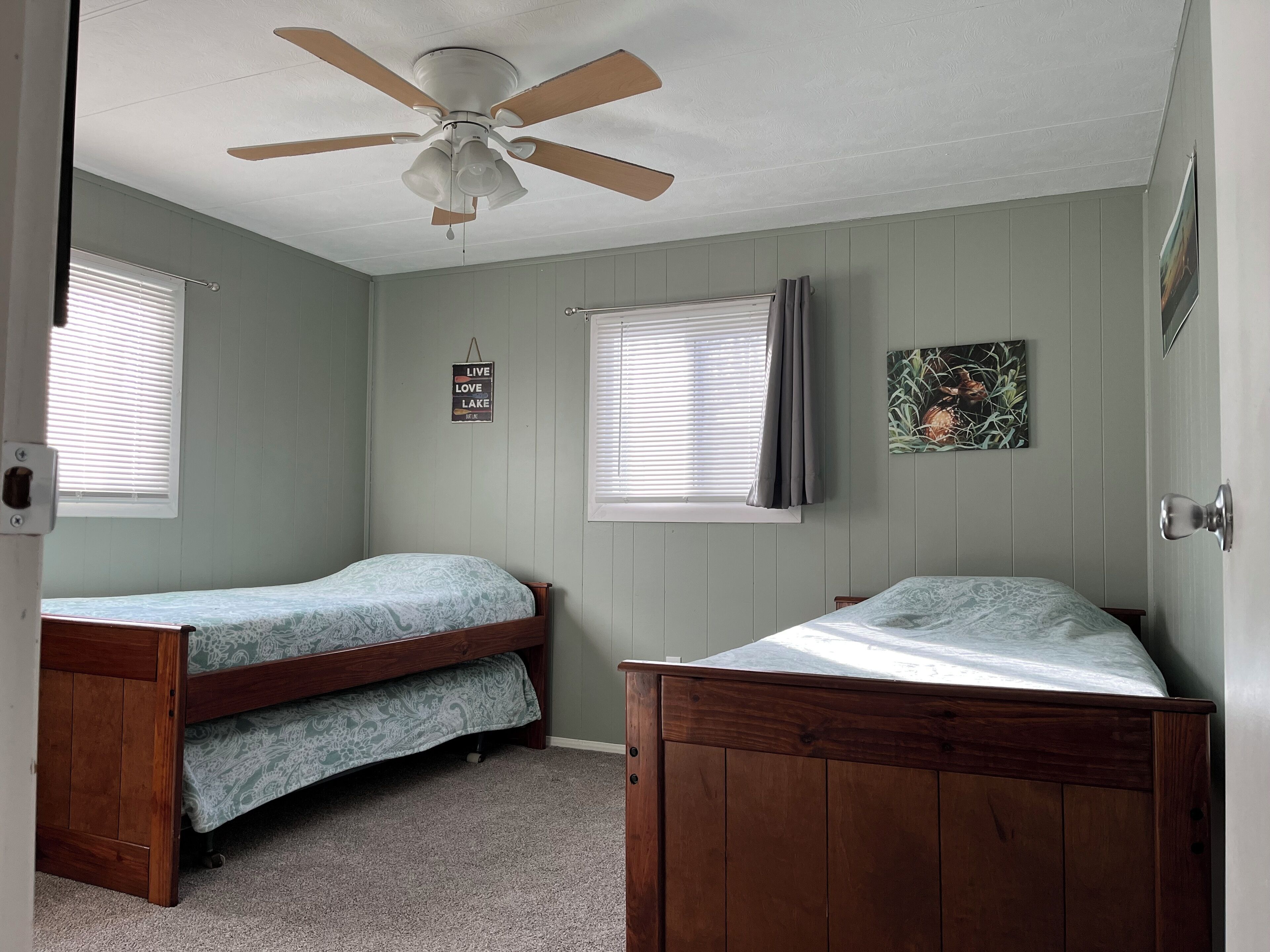 A bedroom with two beds, a ceiling fan, and a sign on the wall.