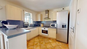 Una cocina moderna con una isla grande, horno empotrado, microondas y refrigerador.