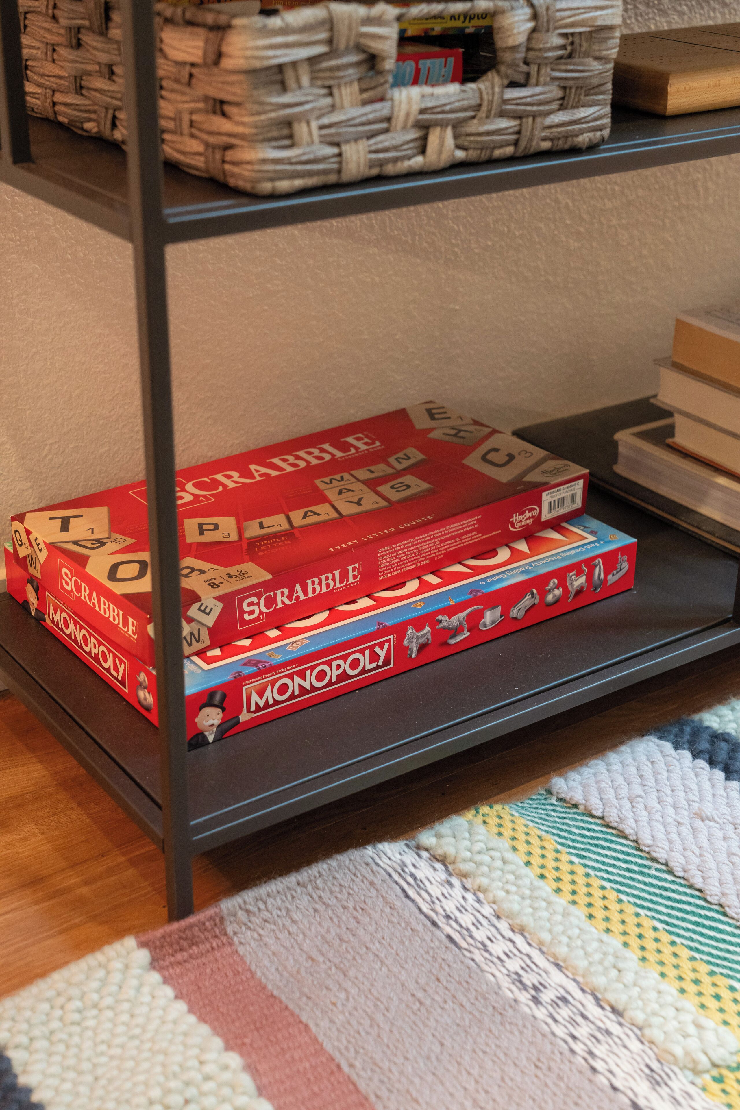 A shelf with board games, including Scrabble and Monopoly, and a woven basket in the background.