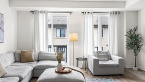 Una sala de estar moderna con un sofá modular, una mesita auxiliar, una lámpara de pie y una planta en maceta.