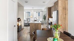 Una cocina moderna con armarios de madera, una isla central y un comedor con mesa y sillas.