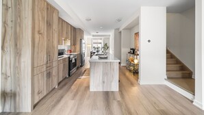 Una cocina moderna con armarios de madera, una isla central y una escalera que sube a otro nivel.
