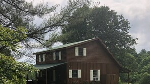 A two-story wooden house with a covered porch and a grassy yard. - Christmas Cabin in Hocking Hills (New Marshfield, Ohio)