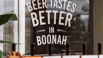 A window with the text "THE BEER TASTES BETTER IN BOONAH" and a view of a building with palm trees.