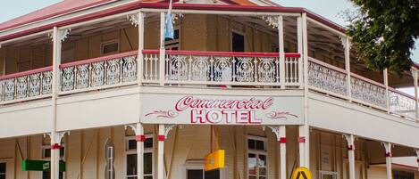 A two-story building with a balcony, a sign reading 'Commercial Hotel,' and a pedestrian crossing sign.