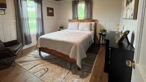 Een slaapkamer met een houten bed, een bureau en een stoel.