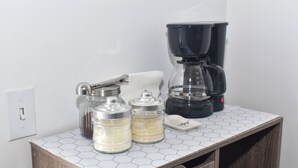 Eine Küchenarbeitsplatte mit einer Kaffeemaschine, Zuckerdosen und einem Messer.