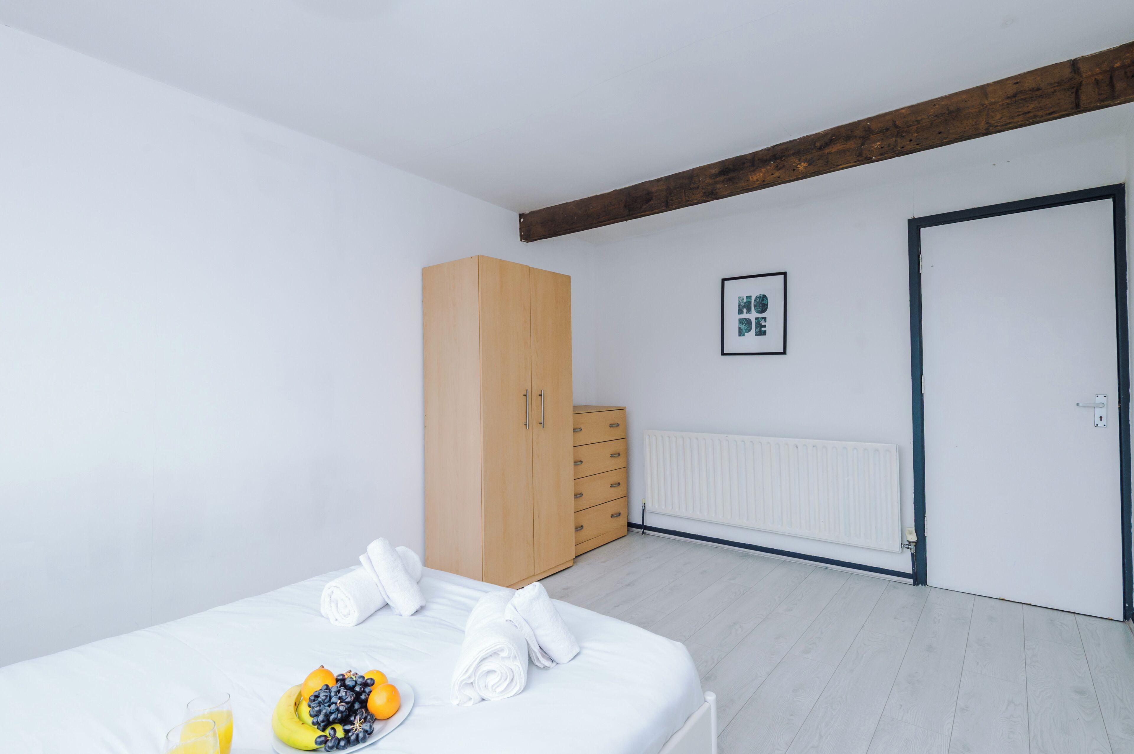 A bedroom with a bed, a wardrobe, a radiator, and a door.