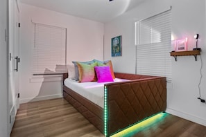 A modern bedroom with a bed, white walls, and a wooden floor. - Game Night Getaway - 3BR Near WinStar (Thackerville)