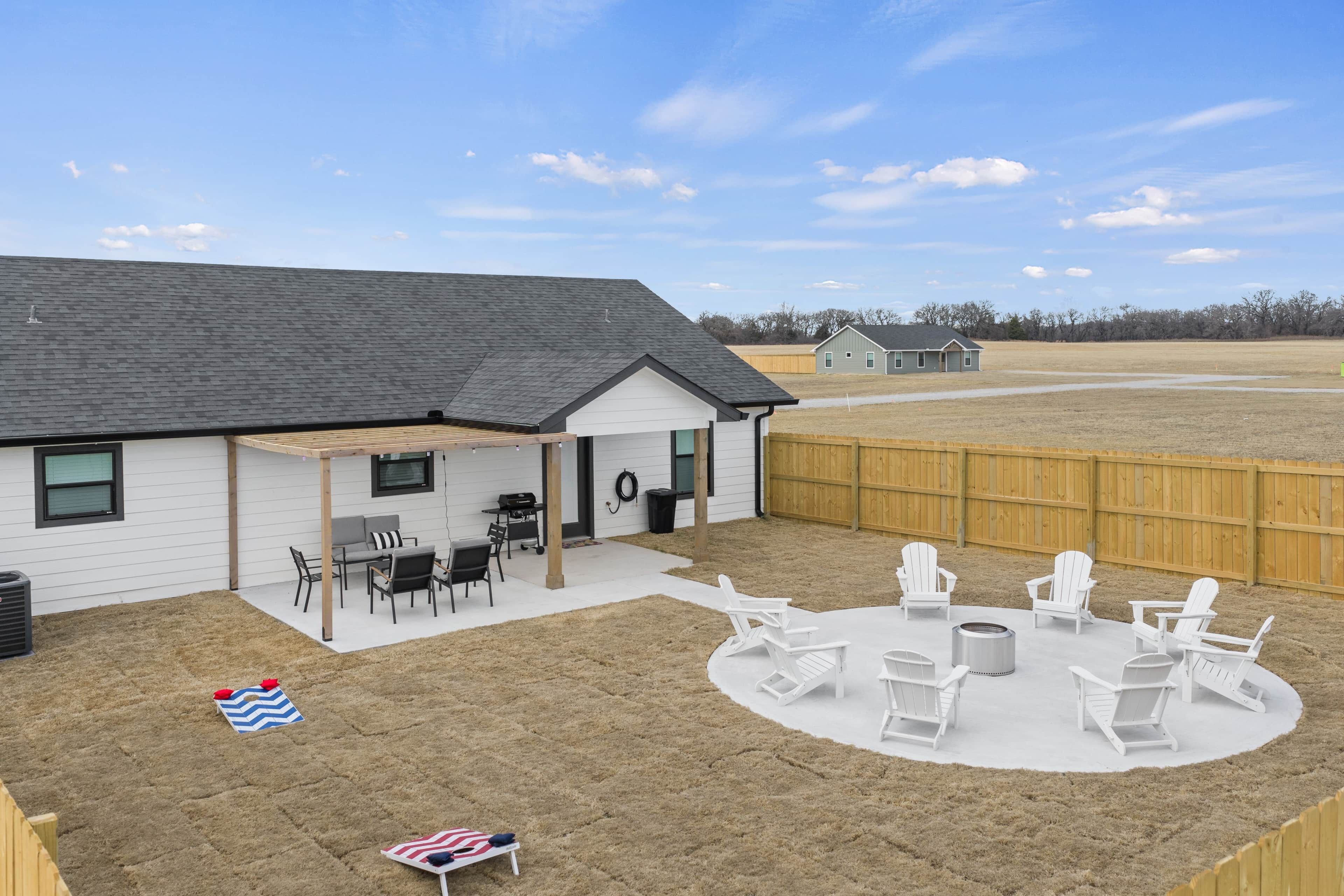 A backyard with a covered patio, outdoor seating, and a fire pit area.