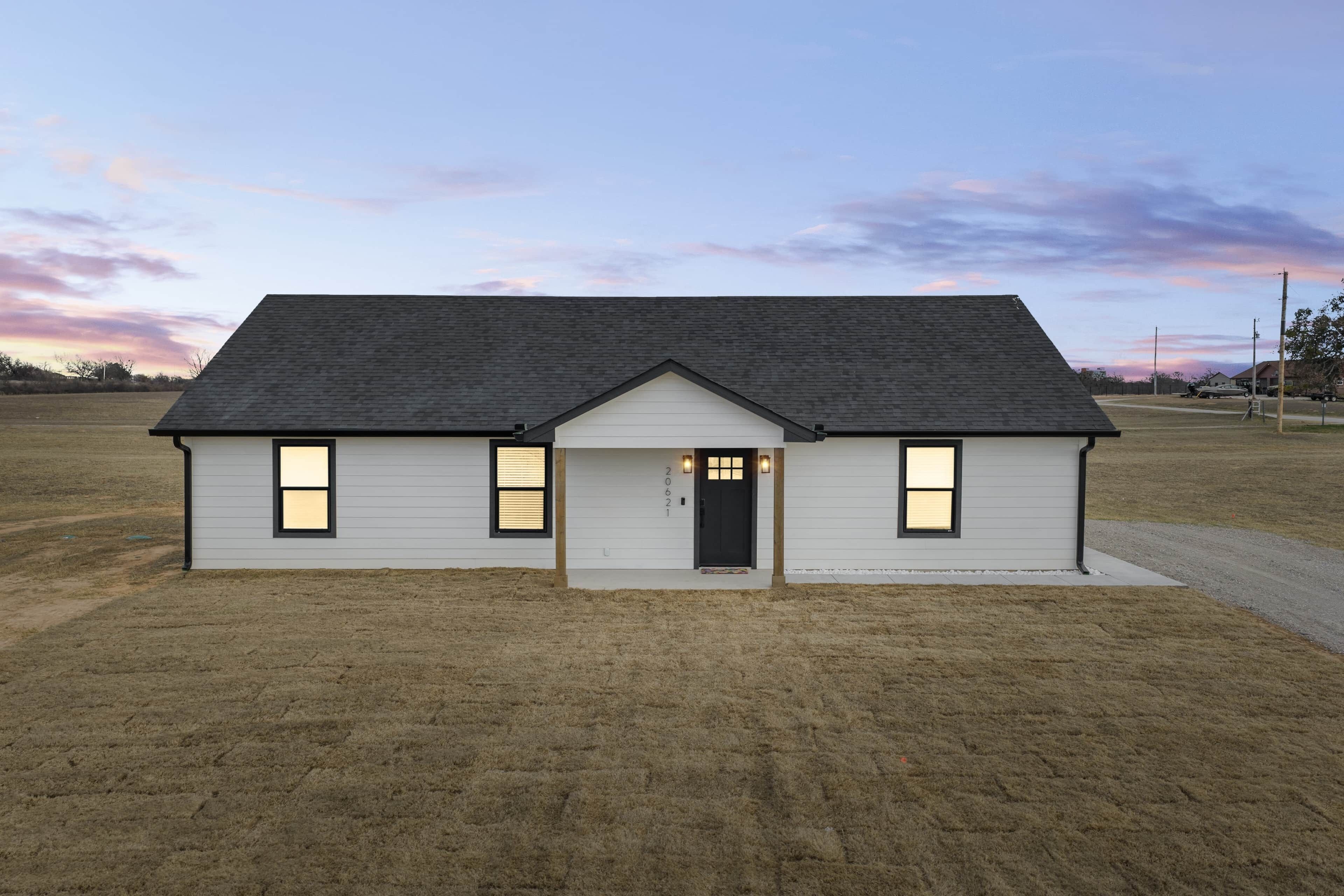 A single-story house with a gabled roof, a front door, and two windows on each side.