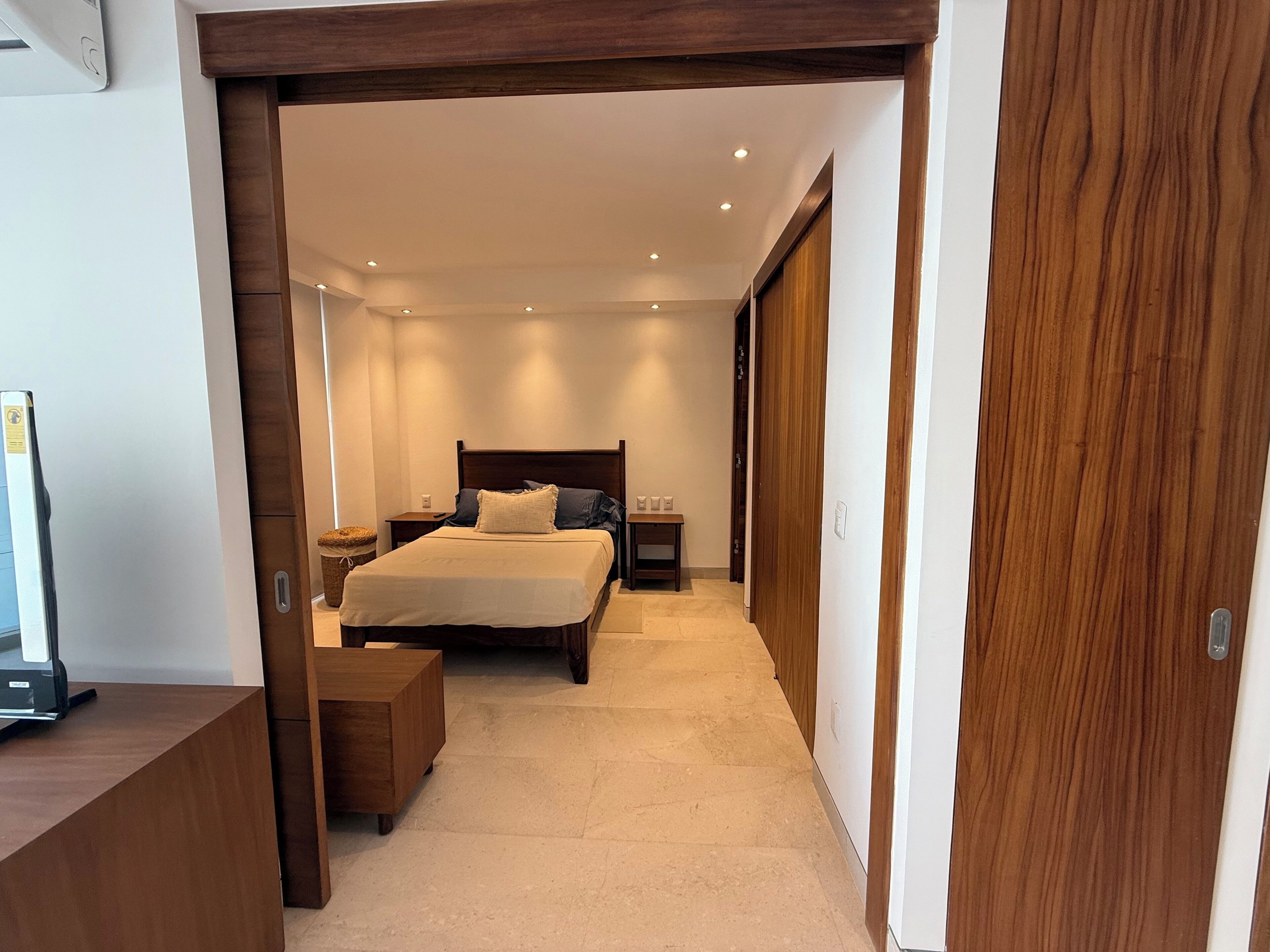 A bedroom with a bed, bedside tables, a wooden bench, and a wardrobe.