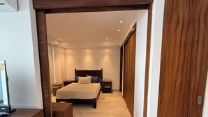 A bedroom with a bed, bedside tables, a wooden bench, and a wardrobe. - Bucerias Beachfront Condo (Bucerías)