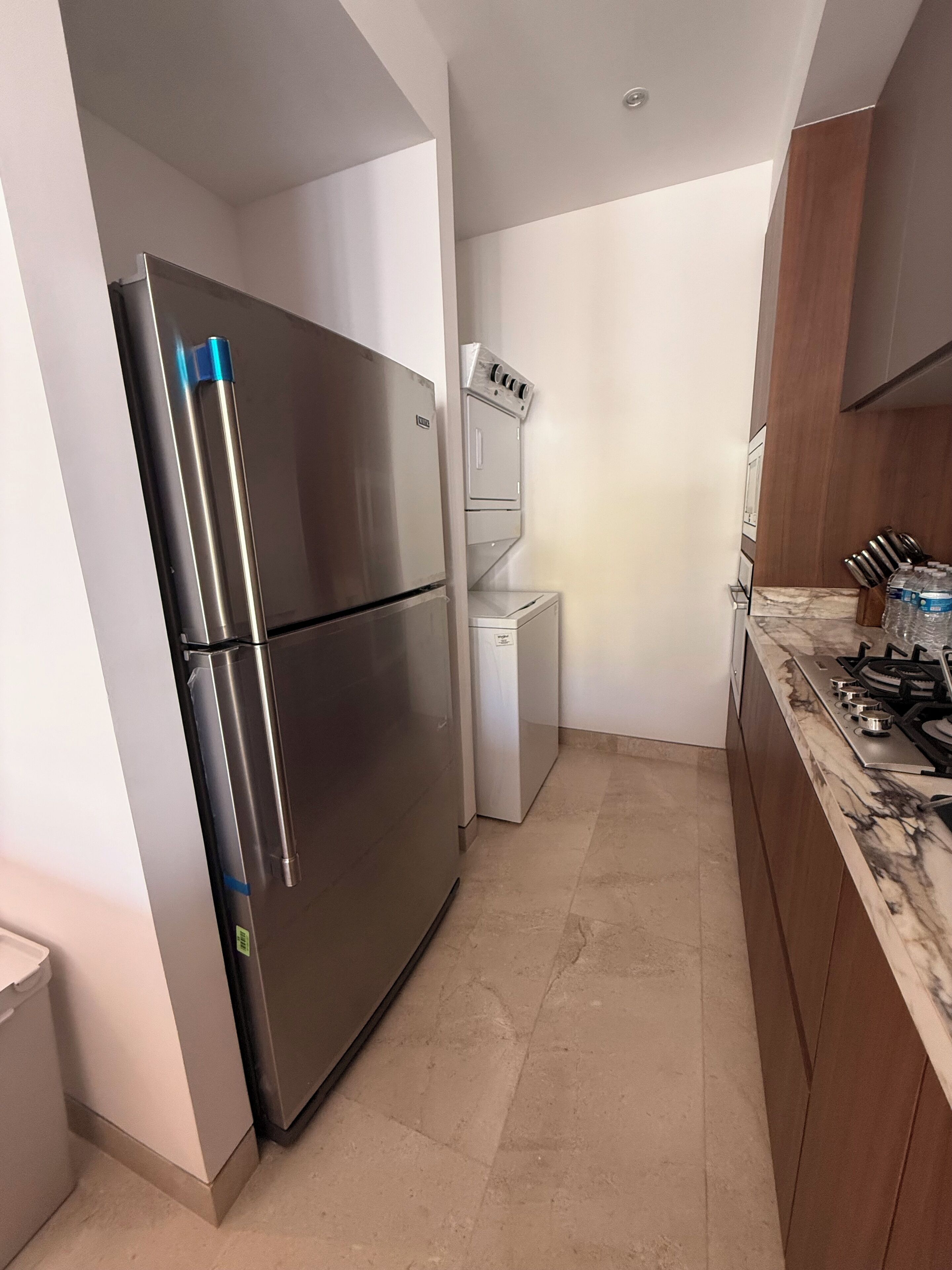A kitchen with a stainless steel refrigerator, a built-in oven, and a stove.