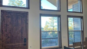 A room with large windows, a wooden door, and a dining table with chairs. - EARLY CHECK IN/OUT 1PM Luxury Home on POND in Torreon-Hot Tub & Kids Zone (Show Low)