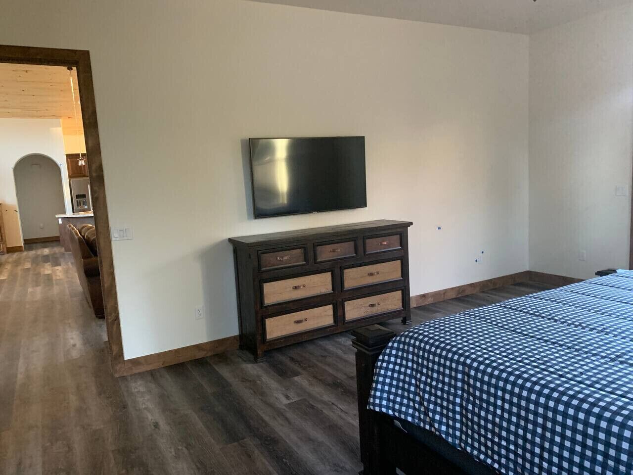 Une chambre à coucher avec un lit, une commode et un téléviseur fixé au mur.