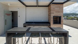 Een buitenpatio met een tafel, stoelen, een spoelbak en uitzicht op een stadsgezicht.