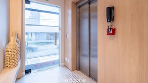 Een hotelingang met een 'Saída'-bord, een lift en een telefoon aan de muur.
