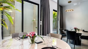 A modern dining area with a round table, chairs, and a vase with flowers. - Anoya Boutique Villa (Kerobokan)