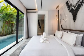 A modern hotel room with a large bed, a view of a swimming pool, and a marble wall. - Anoya Boutique Villa (Kerobokan)