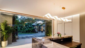 A reception area with a marble counter, potted plants, and a view of the outside. - Anoya Boutique Villa (Kerobokan)