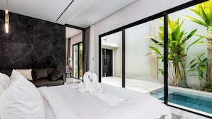 A modern hotel room with a large bed, a dark marble wall, and a view of a swimming pool. - Anoya Boutique Villa (Kerobokan)