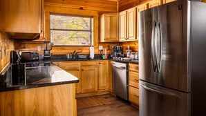 Une cuisine moderne avec des meubles en bois, un réfrigérateur en acier inoxydable et un plan de travail noir.