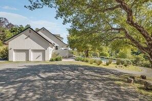 A two-story house with a garage, surrounded by trees and a small pond. - Private Oasis in Healdsburg: Pool, Spa & Views (Healdsburg)