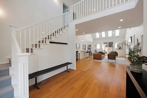 A spacious living area with a wooden floor, a staircase with white railings, and a bench. - Private Oasis in Healdsburg: Pool, Spa & Views (Healdsburg)