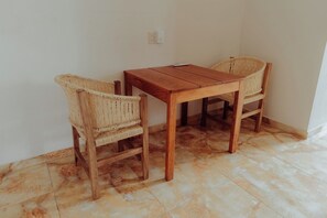 A wooden table with two wicker chairs in a room with tiled flooring. - Private 1BR-Pool-AC-La Punta-Private Kitchen & Bath (Brisas de Zicatela)