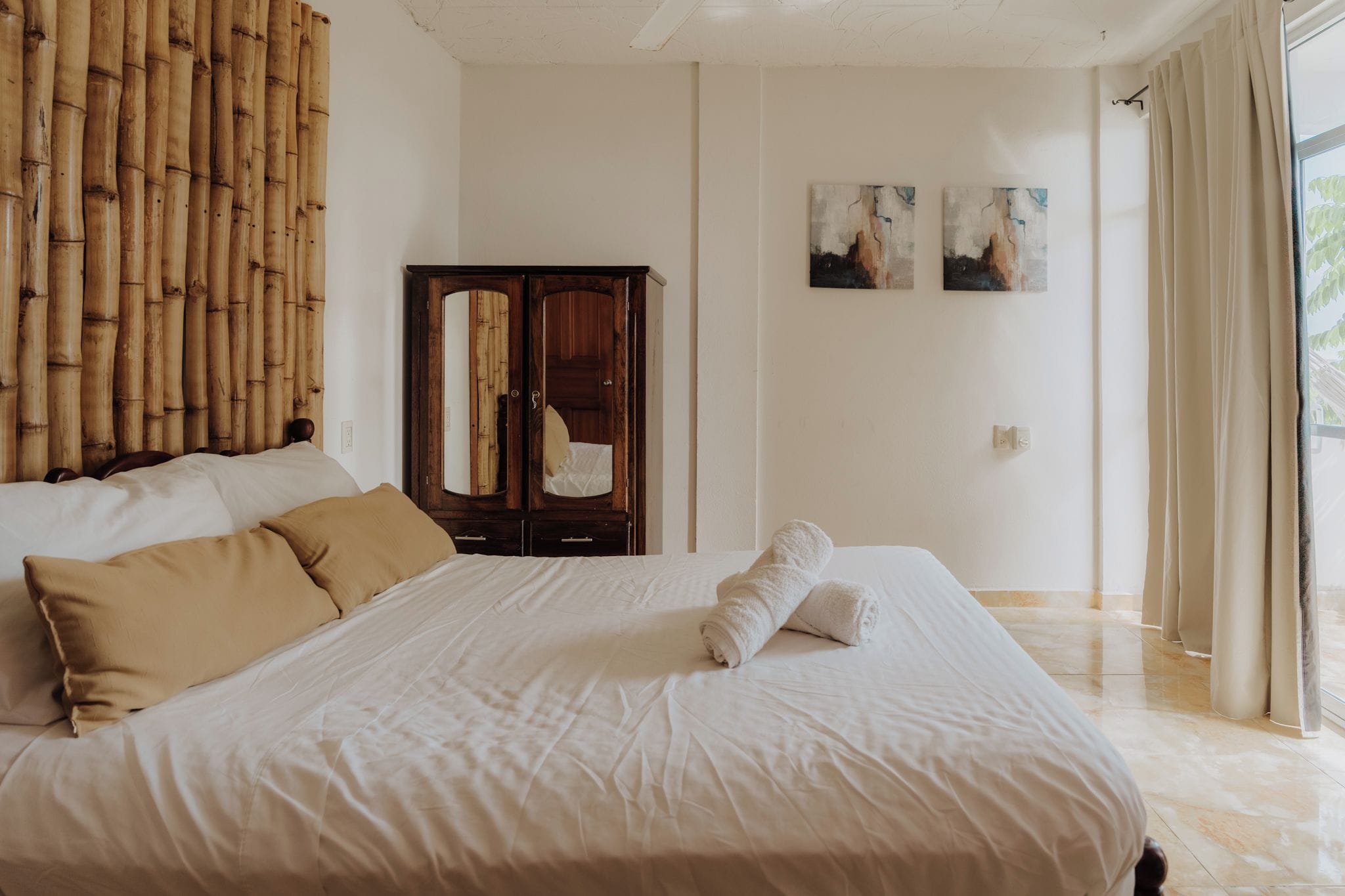 Une chambre d’hôtel avec un grand lit, une armoire en bois et une vue sur l’extérieur.
