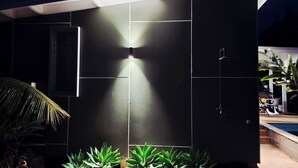 A modern building with a dark facade, a visible water feature, and a pool area. - The Green House (Rarotonga)