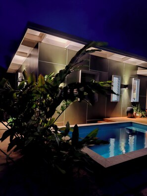 A modern pool area with a clear pool, surrounded by dark-toned walls and minimalistic design. - The Green House (Rarotonga)