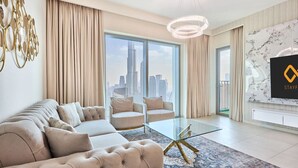 A modern living room with a sofa, armchairs, a glass coffee table, and a large window with a city view. - Spacious 4-Bedroom Downtown Apartment with Burj Views (Dubai)