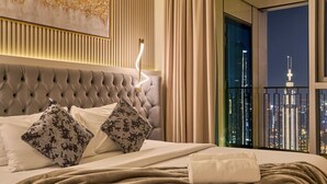 A luxurious bedroom with a tufted headboard, patterned pillows, a neatly made bed, and a view of a city skyline at night. - Spacious 4-Bedroom Downtown Apartment with Burj Views (Dubai)