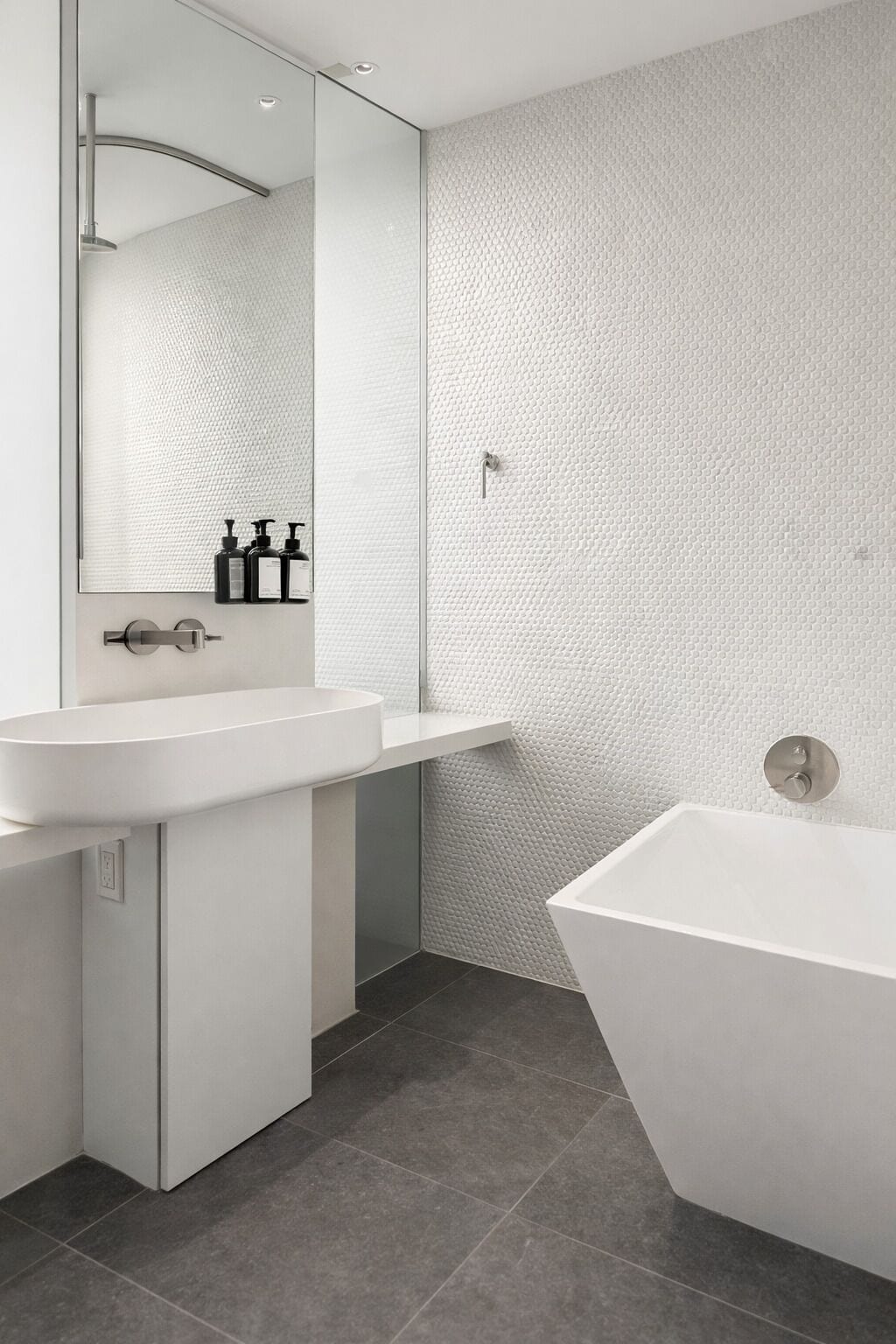 A modern bathroom with a freestanding bathtub, a large mirror, and a white sink.
