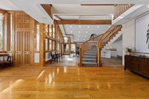 Un interior amplio con una escalera de madera, ventanas grandes y una zona de cocina moderna.