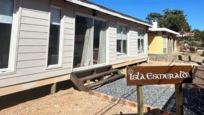 Edessä on rakennus, jossa on suuret ikkunat ja puinen terassi, ja sen edessä on puinen kyltti, jossa lukee ”Isla Esmeralda”.