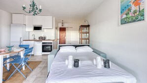 A modern hotel room with a bed, a small kitchenette, a dining area, and a bathroom. - Studio Merle - Welkeys (Bandol)