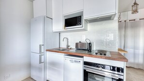 A modern kitchen with white cabinetry, a built-in microwave, a toaster, and a dishwasher. - Studio Merle - Welkeys (Bandol)