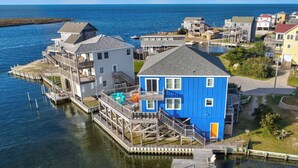 Una propiedad frente al agua, con un muelle, una casa azul y una casa gris.