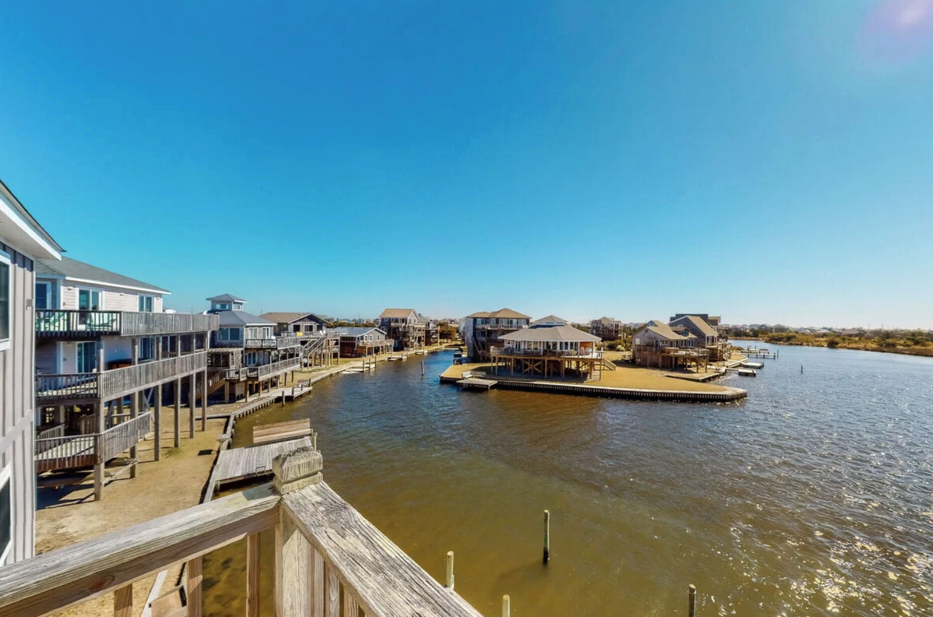 A waterfront property with multiple houses connected by wooden walkways over water.