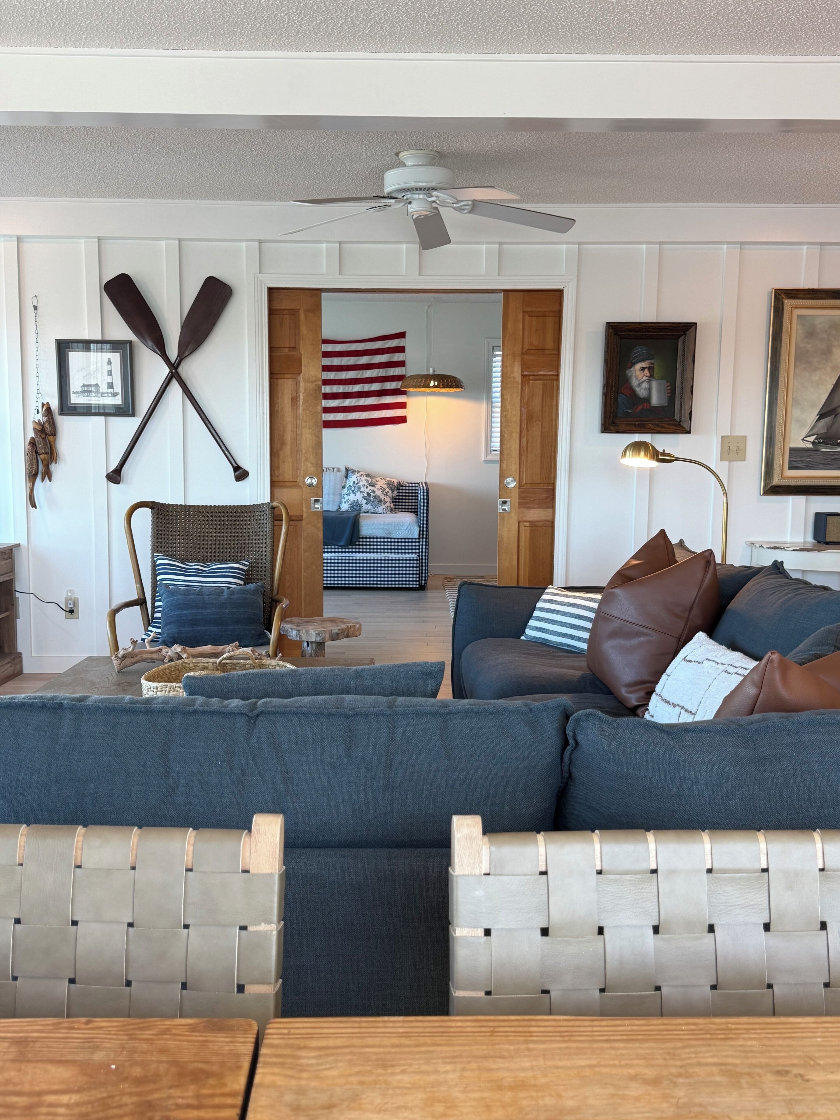 A living room with a sofa, a chair, a table, and a ceiling fan.