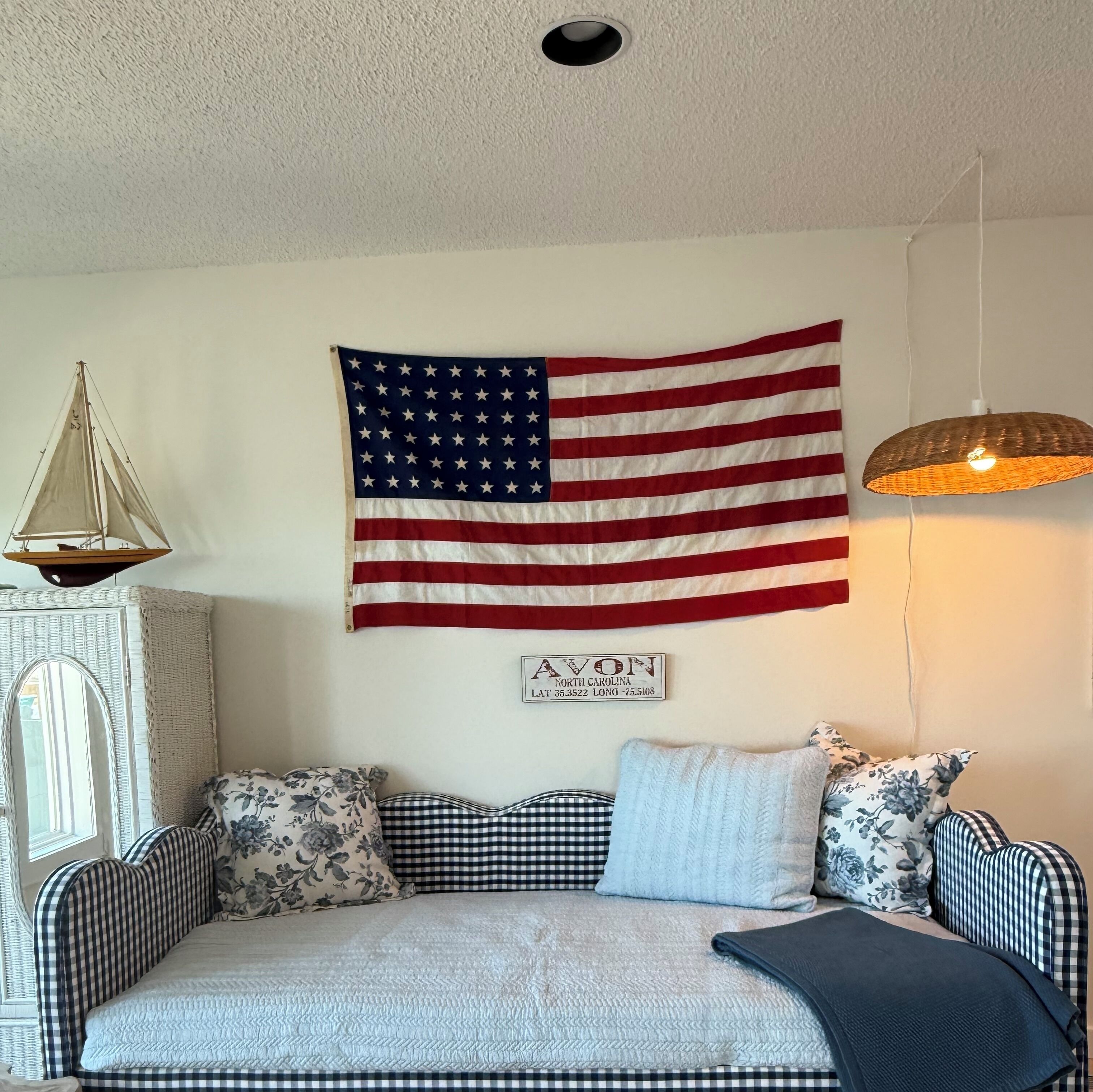 A cozy room with a large American flag, a vintage-style lamp, and a sign with a location.